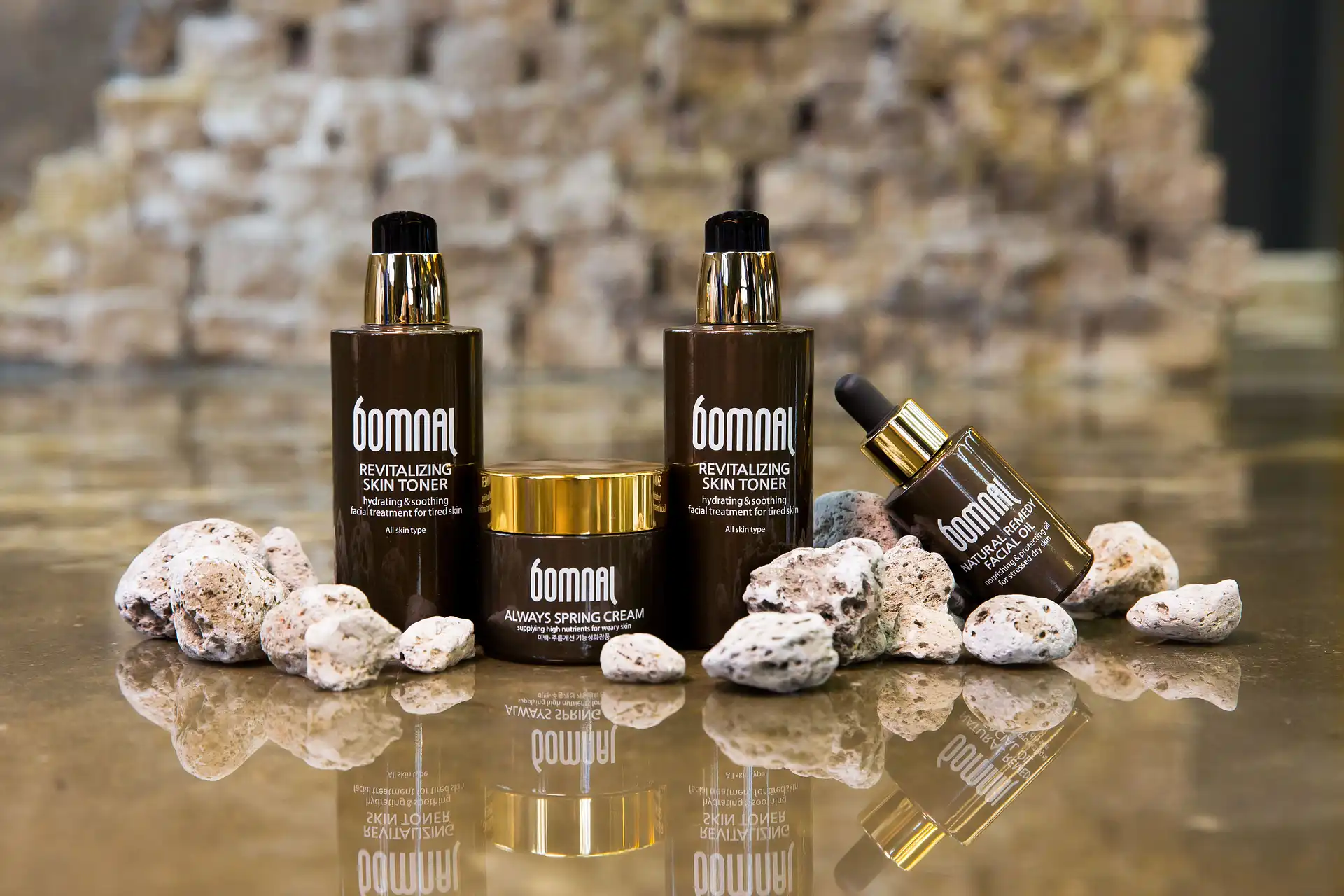 Skincare product bottles arranged among stones on a reflective surface